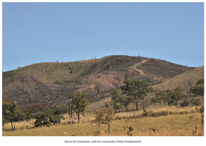  4 w- Morro do Centenário onde foi lançada a Pedra Fundamental. Esse ambiente é retratado com bastantes arvoredos e o morro com árvores em tamanhos e formatos diversos, com a paisagem complementada por terras e pedregulhos. No alto do morro, segue-se  uma estrada de terra. Realização: Academia Planaltinense de Letras, Artes e Ciências (APLAC), pelo Ecomuseu Pedra Fundamental e pelo Coletivo Nativo Audiodescrição produzida  pelo Instituto de Promoção das Pessoas com Deficiência Visual Audiodescritora: Elma Lúcia Rodrigues Consultor: Fernando Rodrigues Este projeto é promovido com recursos do Fundo de Apoio a Cultura do DF